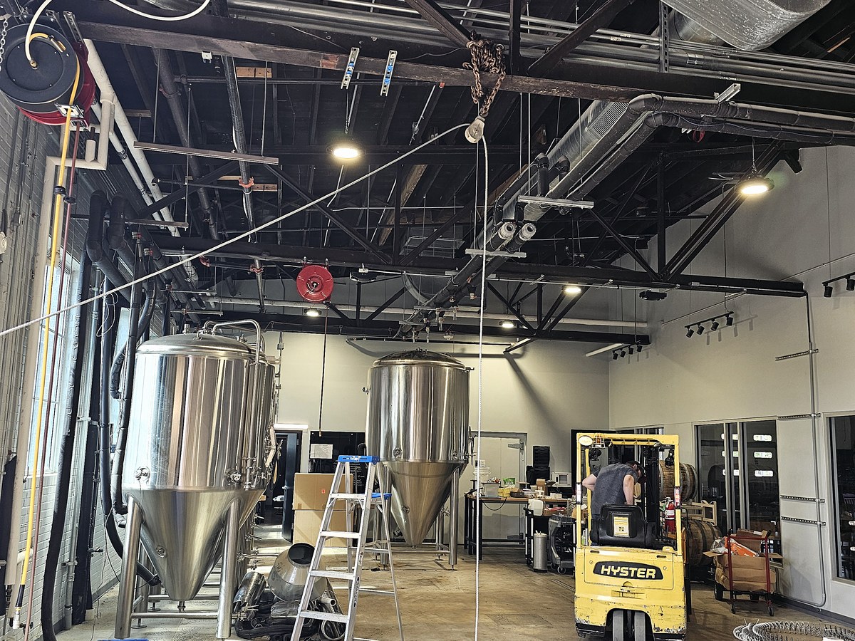 Chain hoist rigged from a ceiling beam above two fermenters during a removal